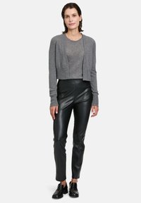 Cardigan gris court et pantalons en cuir noirs ajustés. Le cardigan présente des manches longues et un design à l'avant ouvert, avec une texture côtelée.