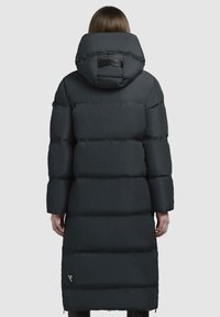 Lungo cappotto puffer grigio scuro, con cappuccio, design trapuntato e logo sopra il colletto. Tasche con zip sui lati.