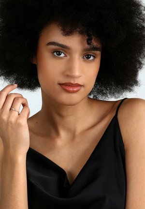 Black satin top with a draped neckline, worn by a model with curly hair. She is showing a delicate ring with a clear stone on her left hand.