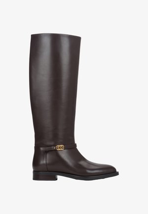 Brązowy skórzany kozak sięgający kolan o gładkiej fakturze, płaskiej podeszwie i złotym ozdobnym pasku z klamrą. Cechuje go zaokrąglony nosek i elegancki design.