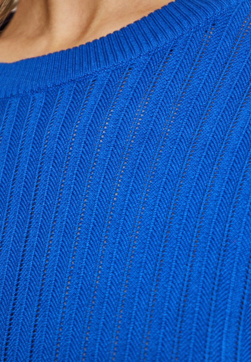 Top blu lavorato a maglia con texture a coste e fantasie a spina di pesce verticali, scollatura rotonda e dettagli in filato fine.