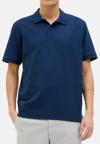 Polo shirt blu navy in un tessuto texture con colletto classico, maniche corte e un sottile logo accento sul petto.