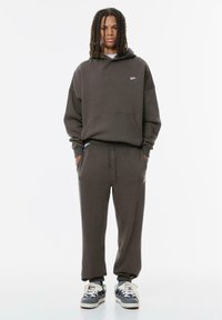 Mörkgrå sweatshirt och matchande sweatpants i bomullsblandning. Huva med framficka och elastiska ärmslut. Sneakers med vita snören.