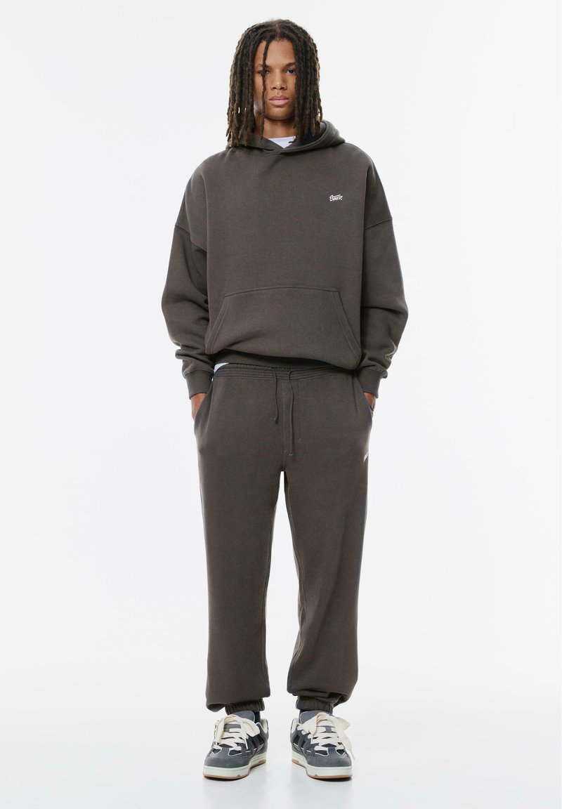 Mörkgrå sweatshirt och matchande sweatpants i bomullsblandning. Huva med framficka och elastiska ärmslut. Sneakers med vita snören.