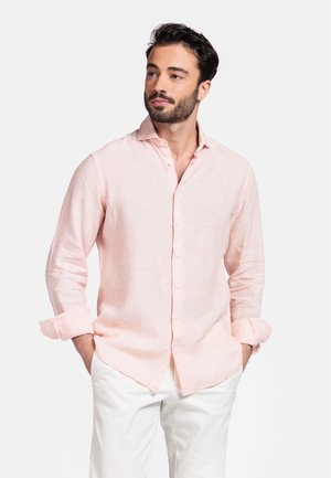 Lichtroze linnen shirt met een button-down kraag en opgerolde mouwen, gecombineerd met witte broek. Eenvoudig en casual ontwerp.