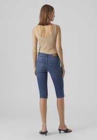 Τζιν βερμούδες σε σκούρο μπλε χρώμα με εφαρμοστή σχεδίαση, που διαθέτουν δύο πίσω τσέπες, μέση μεσαίου ύψους και γυριστό στρίφωμα.