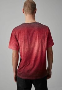 Camiseta de manga corta en degradado rojo, con un patrón texturizado. El color transita de un rojo brillante a tonos más oscuros.