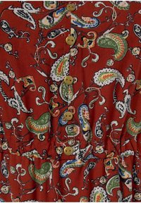 Rotes gestreiftes Kleid mit Paisleymustern in Grün, Weiß und Blau, mit gelben Knöpfen auf der Vorderseite und einer gerafften Taile.