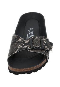 Zwart-witte sandalen met slangenpatroon, voorzien van een kurken zool en een verstelbare gesp. Zachte voetbed met een gladde zwarte binnenkant.