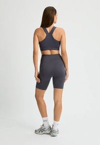 Mörkgrått träningsset med en sport-bh med justerbara band och högmidjade shorts, tillverkade av andningsbart och stretchigt material.