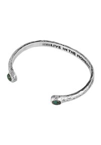 Silver cuff bracelet featuring a textured surface and two small green stones, with "LIVE IN THE MOMENT" engraved on the inside.