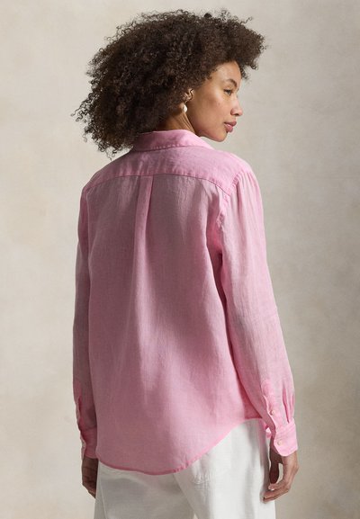Ljusrosa skjorta med lång ärm i linne. Har en knappkrage och en rundad fåll. Lätt textur och avslappnad passform.
