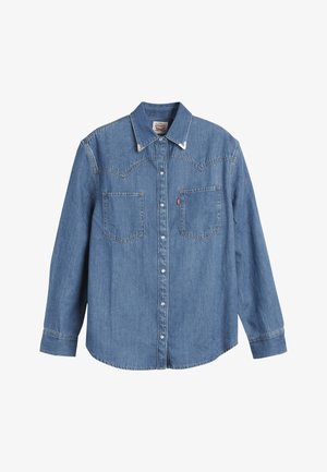 Light blue denim shirt with long sleeves, pointed collar, two chest pockets, and contrasting stitching. Features a western-style yoke design.