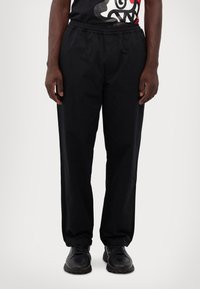 Black athletic pants with an elastic waistband, straight leg design, and lightweight fabric. Paired with black shoes, no visible patterns.