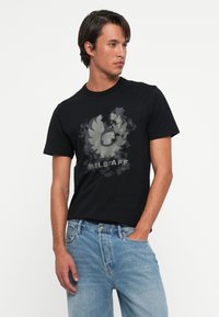 Črna majica s kratkimi rokavi, okroglega ovratnika, izdelana iz lahkotnega bombaža, z grafičnim tiskom v odtenkih sive z zamazanim dizajnom.