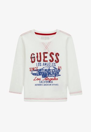 Hvid langærmet skjorte med rød syning og grafik af en blå vintagebil samt teksten "GUESS Los Angeles California" foran.