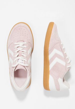 Rosa Wildleder-Sneaker mit weißen Chevron-Streifen, weißen Schnürsenkeln und Gummisohlen in Karamellfarbe, dargestellt von oben und von der Seite auf weißem Hintergrund.