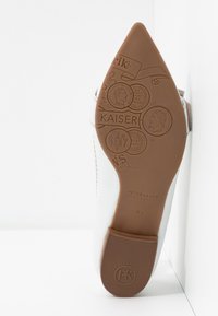 Chaussure en cuir blanc à bout pointu, dotée d'une semelle en caoutchouc marron clair gravée de motifs décoratifs et du nom de la marque "Peter Kaiser".