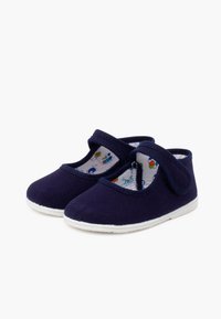 Marineblaue Segeltuchschuhe mit Klettverschluss, weißer Gummisohle und bunten Mustern auf dem Innenfutter. Runde Zehenform, niedrig geschnitten.