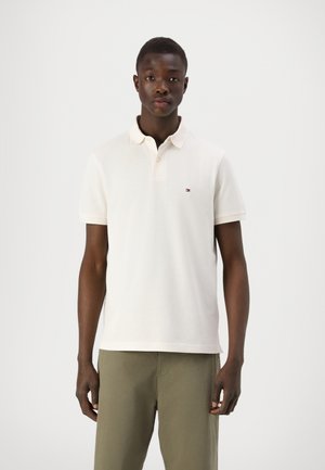 Cream-colored polo shirt made of cotton, featuring a two-button placket, short sleeves, and a small logo on the left chest.