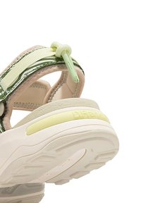 Sandalia multicolor con una suave suela beige, correas verdes, parte superior texturizada y un distintivo acento amarillo en el talón.