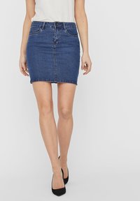 Jeansminikjol i mörkblått med en figursydd silhuett, framknäppning och klassisk femfickdesign. Släthet i texturen, minimal sömnad.