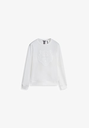 Bijela majica s dugim rukavima koja ima teksturirani dizajn tigrove glave na prednjoj strani, okrugli izrez, dugačke rukave te rebraste manžete i donji rub.