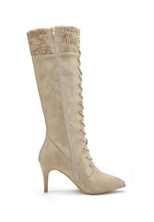 Beige high-heeled boot with a pointed toe, lace-up front, and a textured knit cuff; features a side zipper and smooth suede-like material.
