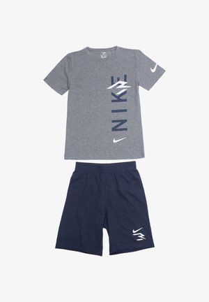 T-shirt en coton gris avec impression verticale "NIKE" en bleu marine et logo blanc ; assorti à un short bleu marine, taille élastique et détail logo blanc.