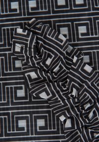 Musta ja valkoinen geometrinen kuvioinen kangas, jossa on teksturoitu pinta, esittää toistuvaa neliösuunnittelua ja kerättyjä yksityiskohtia.