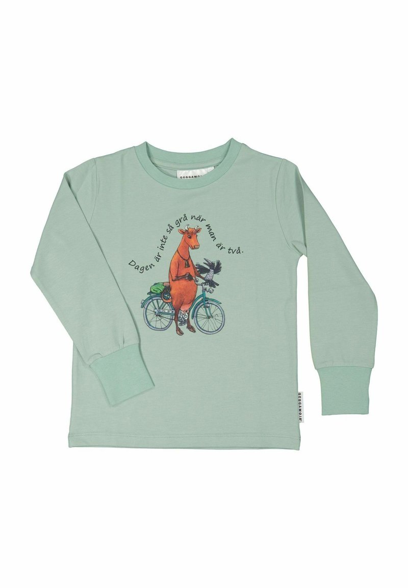 Mintgrön långärmad skjorta med en grafik av en orange ko på en cykel med en fågel, och text i ett cirkelsmönster runt om.