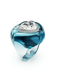 En blå resinring pryds av en stor hjärtformad diamant omgiven av mindre diamanter, vilket visar en lyxig och modern design.