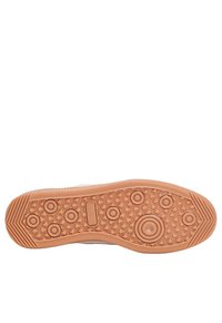 Semelle d'une basket en caoutchouc beige avec des motifs de grip, présentant des éléments circulaires et texturés pour une meilleure adhérence, design à bout rond.