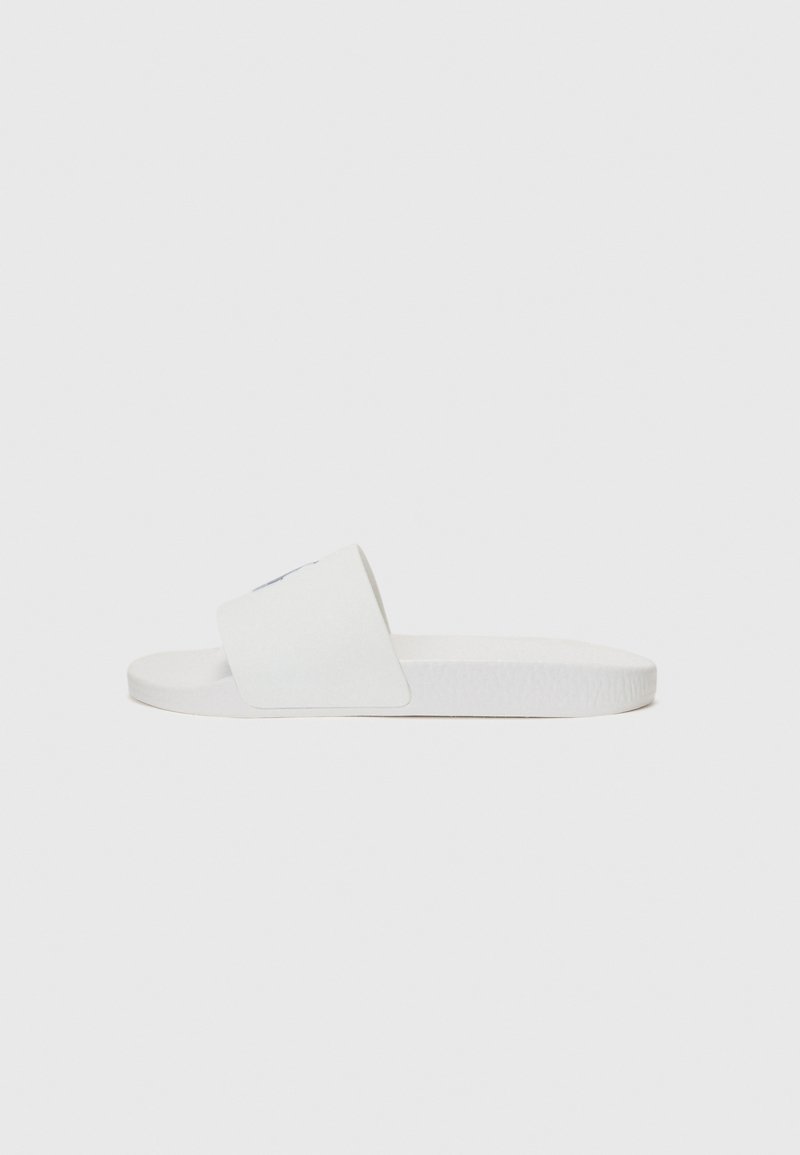 Biely sandál s hladkou, plochou podrážkou a širokým popruhom cez vrchnú časť. Materiál sa zdá byť syntetický a má textúrovaný povrch.