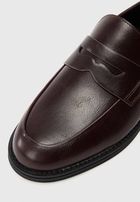 Μπορντό δερμάτινες loafers με λείο φινίρισμα, διακοσμητική ταινία και ραμμένη μαύρη ελαστική σόλα. Στρογγυλή σχεδίαση στην άκρη.