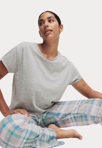 Grijze T-shirt met korte mouwen gecombineerd met multifunctionele geplooide pyjamabroek in verschillende kleuren met blauwe, roze en groene accenten, zachte stoftextuur.