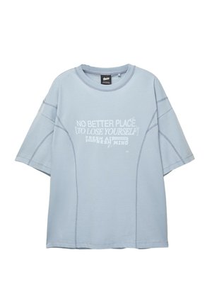 Világoskék, bő szabású pamut póló, környakú, rövid ujjú, elől fehér grafikus szöveggel és varrott díszítéssel.