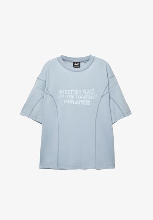 Világoskék, bő szabású pamut póló, környakú, rövid ujjú, elől fehér grafikus szöveggel és varrott díszítéssel.