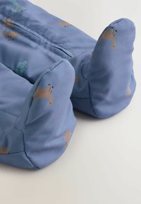 Weicher blauer Stoff mit glatter Textur, der verspielte Tiermuster in Braun und Grün zeigt, geformt mit abgerundeten, gepolsterten Enden.