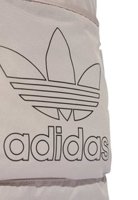 Szürke textúrájú anyag, amelyen egy kiemelkedő fekete körvonalú Adidas trefoil logó és merész "adidas" felirat látható, valamint vízszintes varrási részlet.