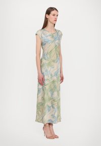 Maxi kjole med blomstermønster i lysegrøn og blå på en bleg beige baggrund, med korte ærmer og en afslappet pasform.