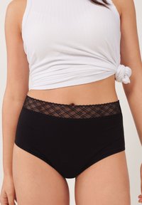 Zwarte high-waisted onderbroek met een geweven kant tailleband met een diamanten patroon. De stof lijkt soepel en rekbaar.
