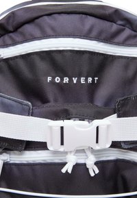 Juodas audinys kuprinė viduje, kuriame matyti baltas tekstas "FORVERT", užtrauktukas, bei baltos petnešos su plastikiniais sagtimis.