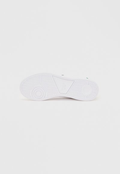 Λευκή σόλα αθλητικού παπουτσιού με κυκλικά και ορθογώνια σχέδια πέλματος πάνω σε απλό ανοιχτό φόντο.