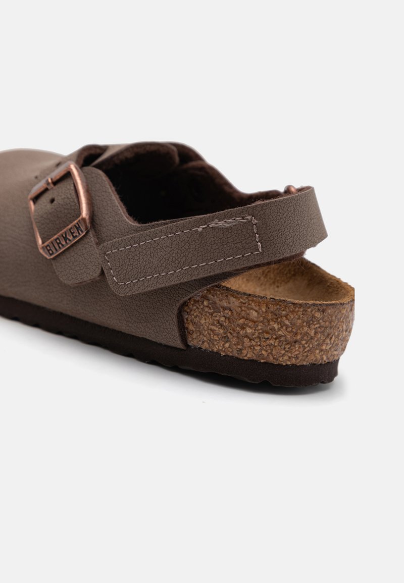 Brązowe skórzane sandały z korkową wkładką, regulowanym paskiem i mosiężnymi akcentami w kolorze miedzi. Podeszwa teksturowana z brązowym wykończeniem gumowym.