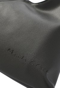 Borsa in pelle nera con superficie texture e logo in rilievo. Il design presenta una forma morbida e floscia e non ha hardware visibile.