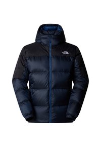 Doudoune matelassée bleu marine avec une capuche, présentant un motif matelassé, des poignets élastiques et un empiècement d'épaule noir contrastant. Fermeture frontale zippée.