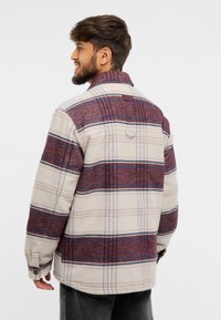 Cămașă din flanel crem cu un model de carouri în nuanțe de vișiniu și albastru, având închidere cu nasturi, mâneci lungi și guler. Material texturat cu un finisaj moale.