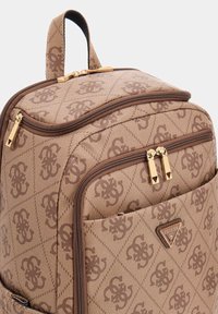 Rucsac maro cu model și finisaj texturat. Are două fermoare aurii, un mâner superior și o plăcuță cu logo pe partea din față.