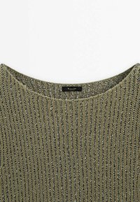 Pull tricoté vert olive avec texture côtelée, col large et accents en fil argenté. Étiquette à l'intérieur indiquant "Mademoiselle D."